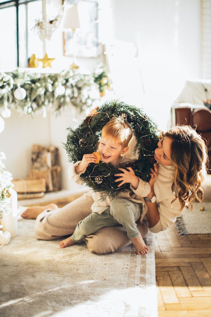 Mother and child enjoying Christmas at home, playing with a festive wreath.